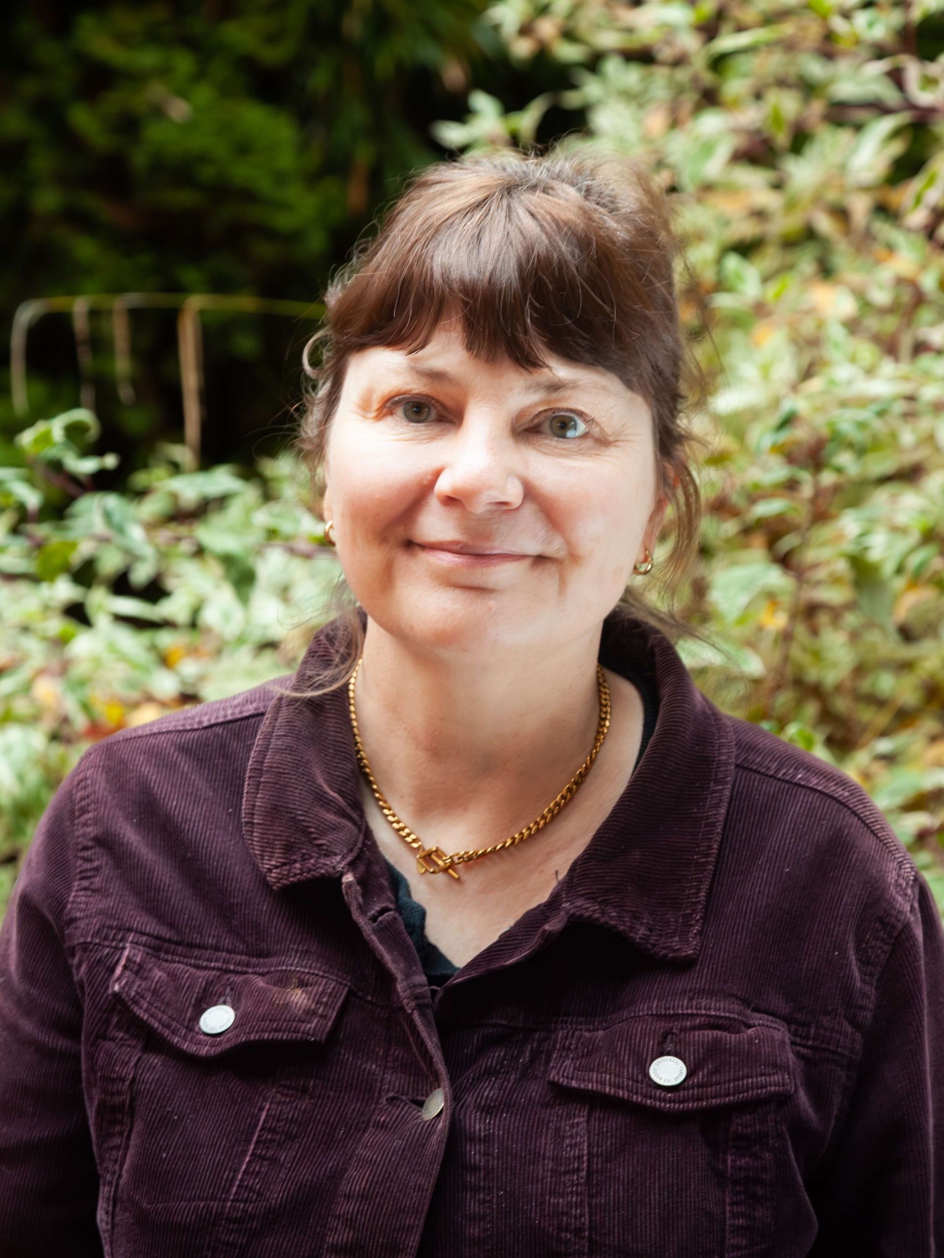 Woman gently smiling wearing a dark purple jacket.