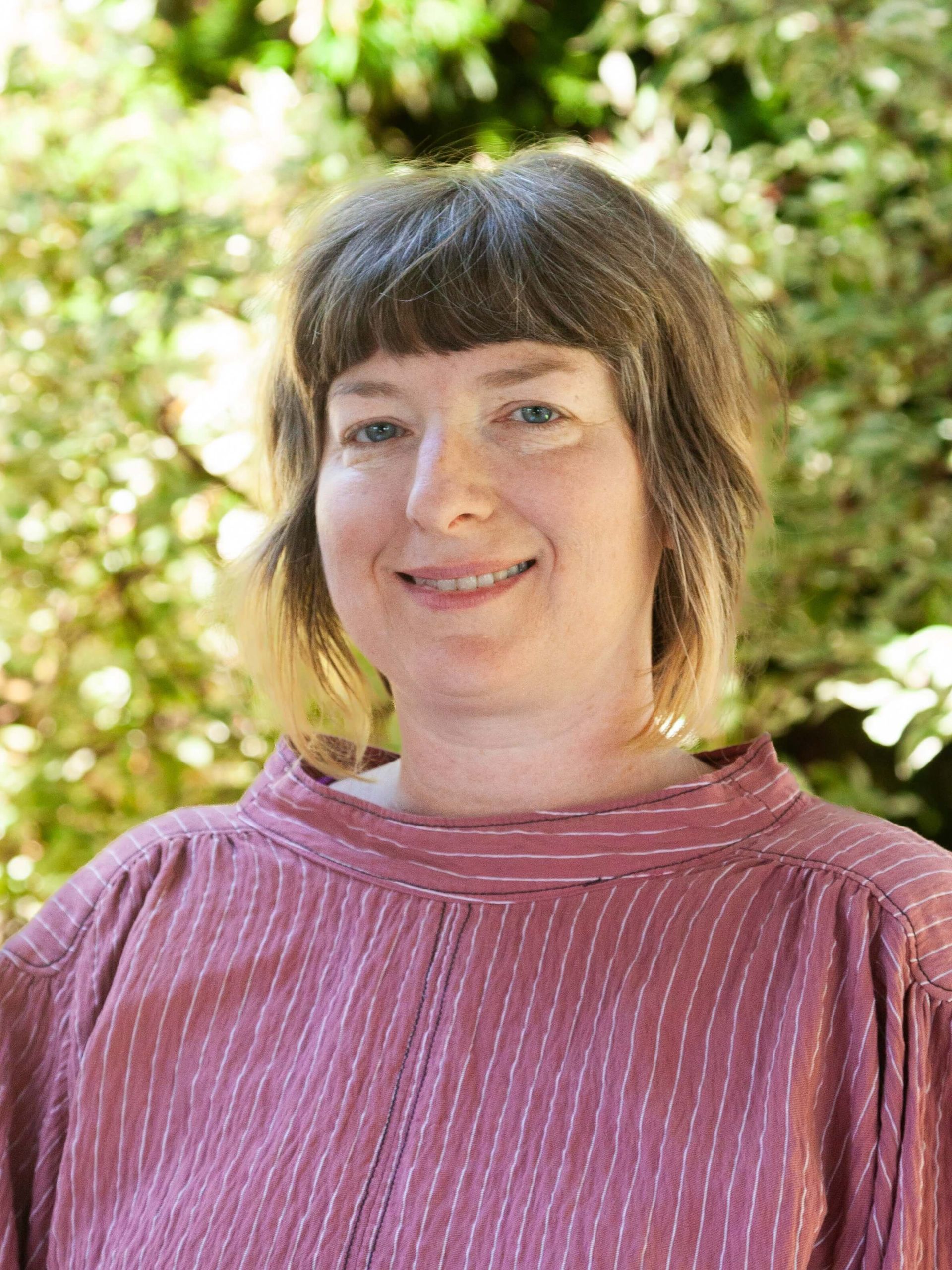Woman gently smiling with short brown hair.