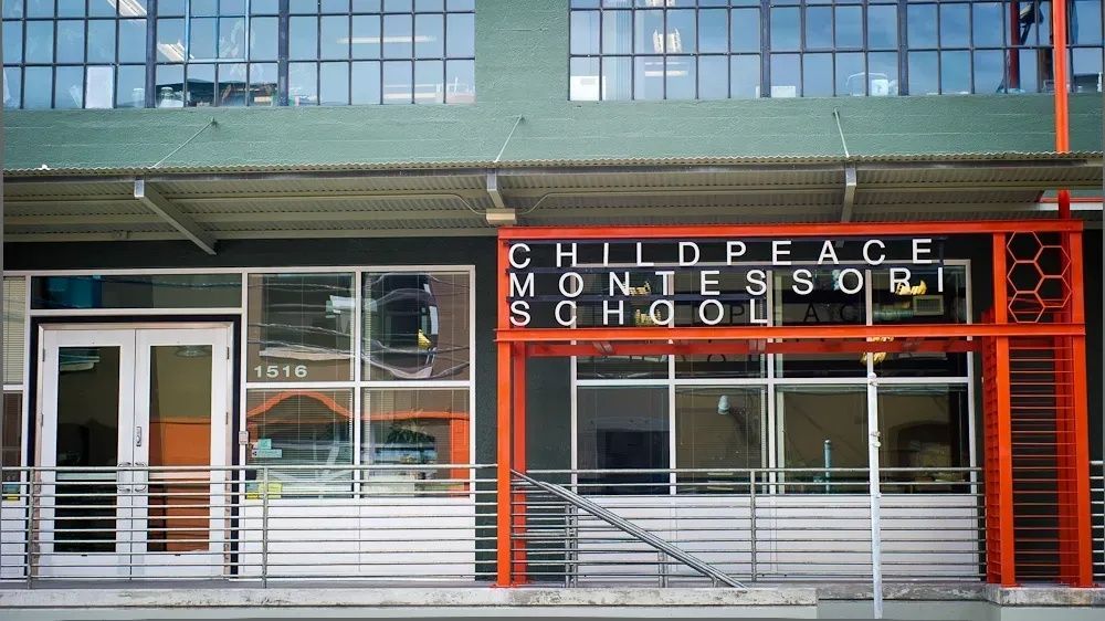 Exterior of the front of Childpeace's main building. Next to the front door is a red metal structure with the name of the school.