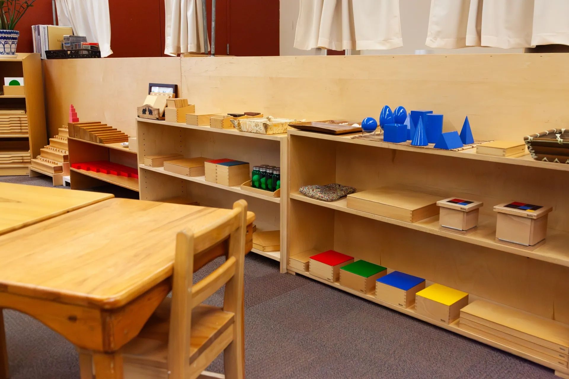 The indoor multi-function room and gym at Childpeace. Large windows span one wall and padded play equipment is arranged in the room.