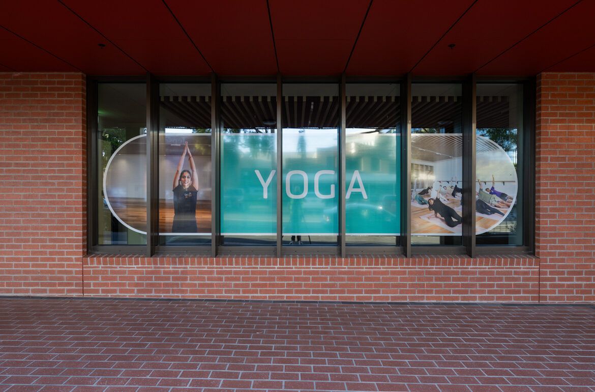 A yoga studio is located in a brick building with a large window.