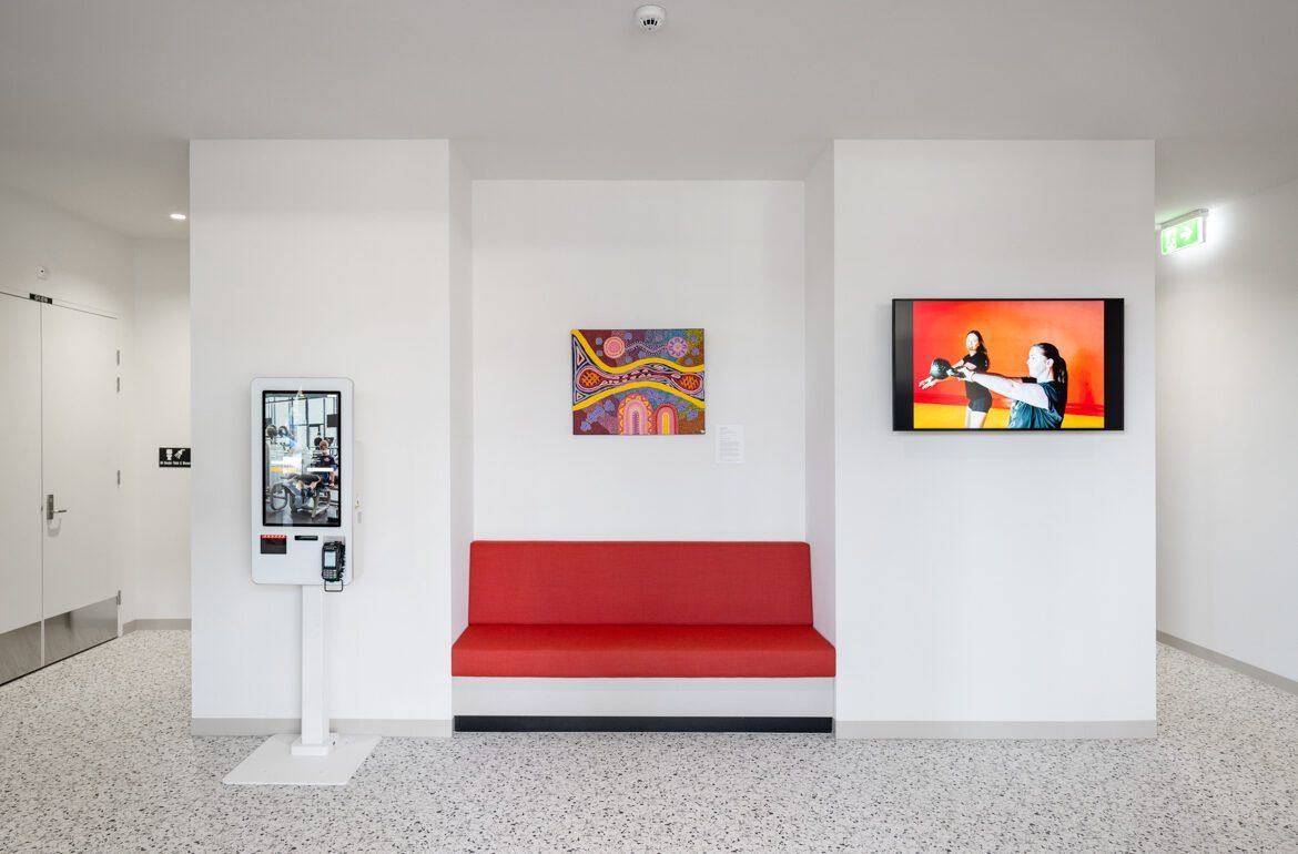 A waiting room with a red couch and a tv on the wall.