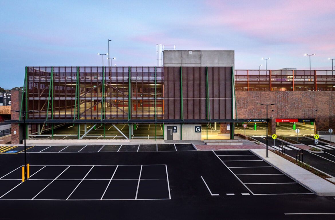 An aerial view of a parking garage with a building in the background.