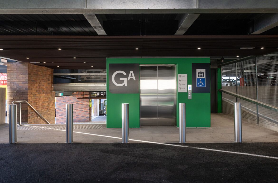 A parking garage with a green wall and an elevator.