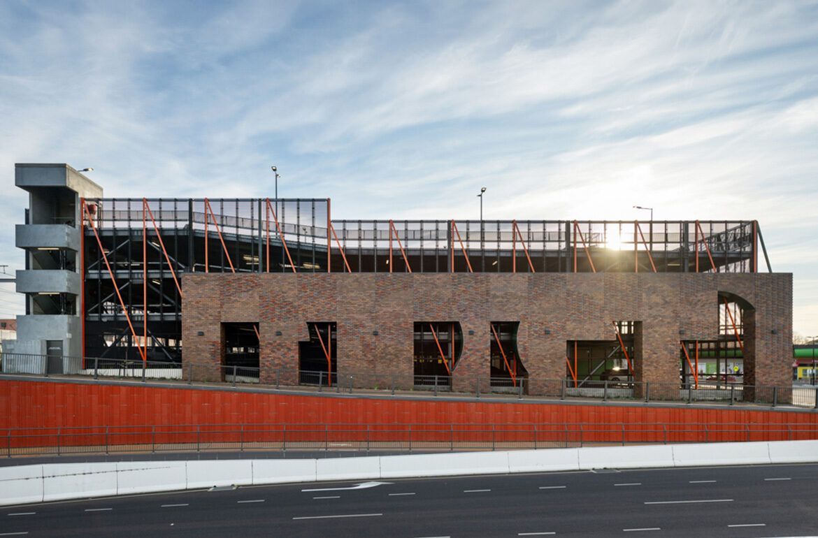 A large brick building is being built next to a highway.