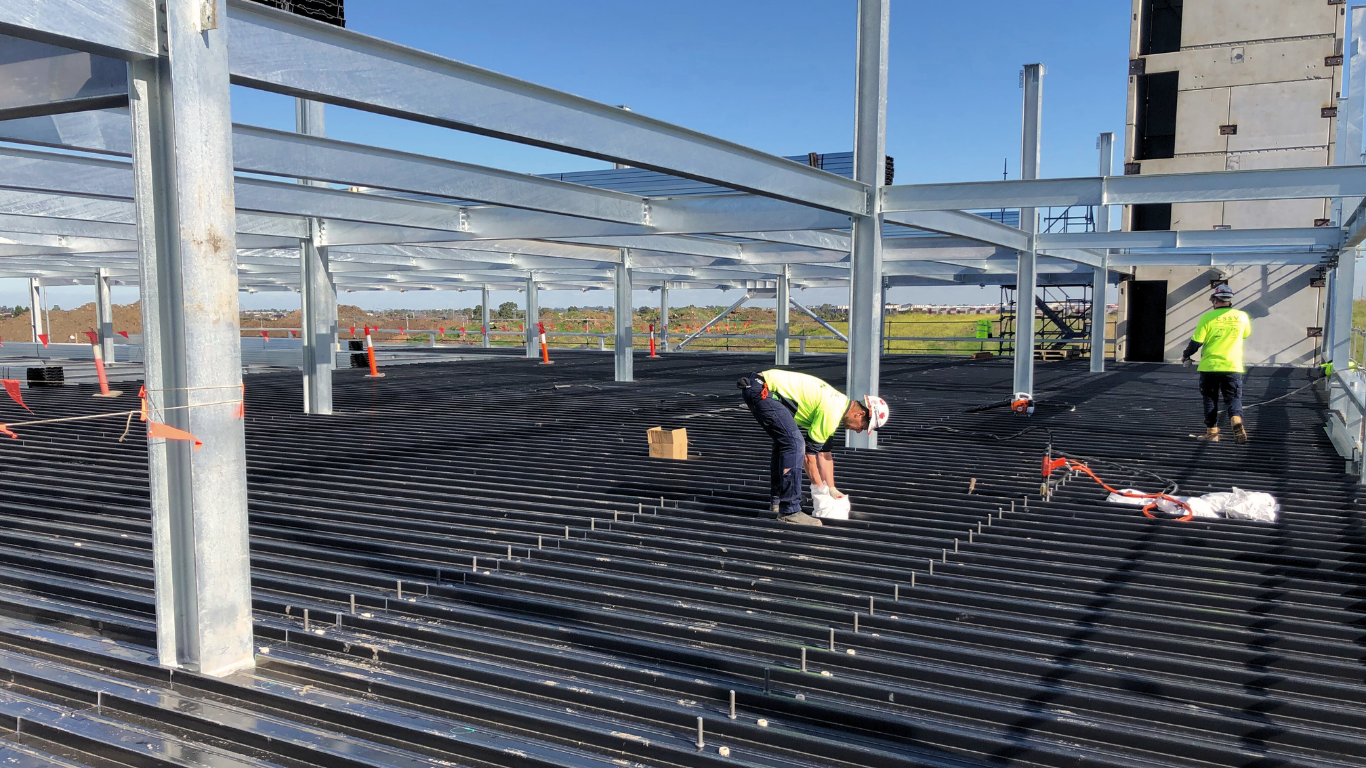 A group of construction workers are working on the floor of a building under construction with reflectorize vest.