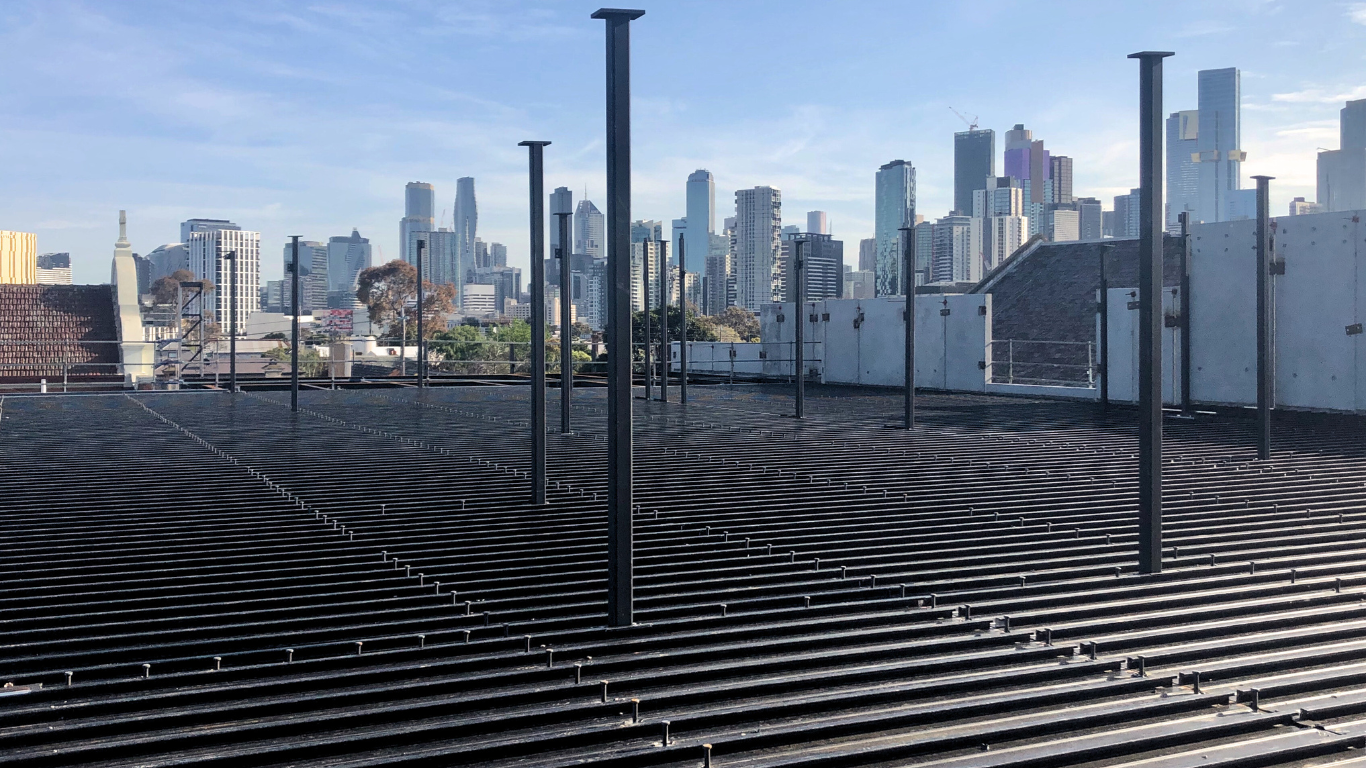 A metal deck with large empty field with a city skyline in the background.