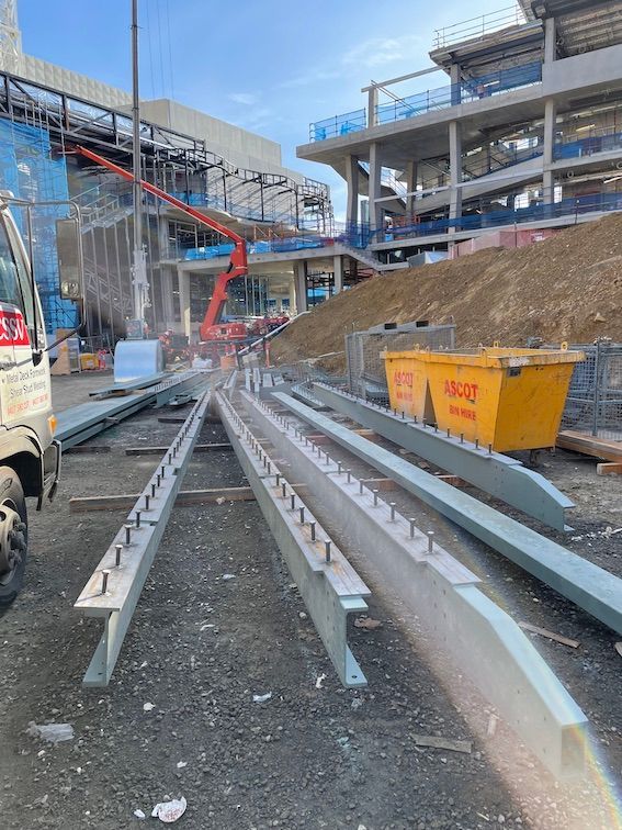A truck is parked in front of a building under construction with Shear Studs