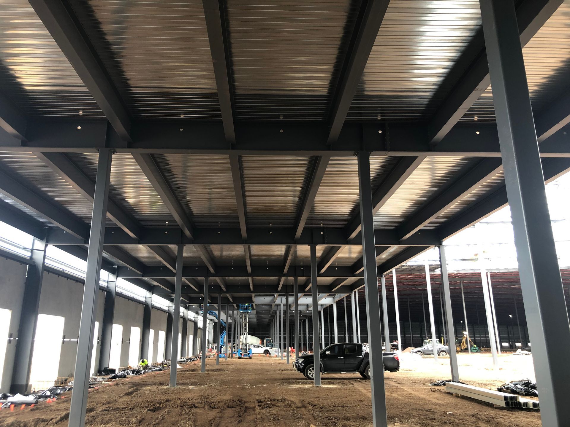 The ceiling of a building under construction with a black truck parked underneath it.