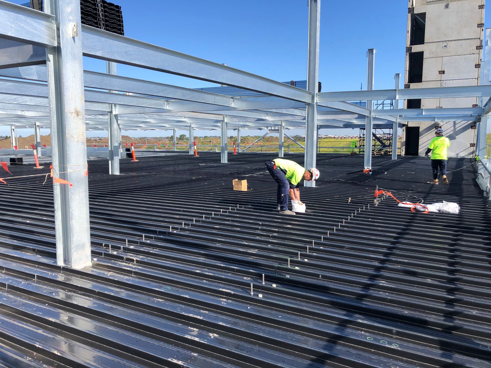 A group of construction workers are working on the floor of a building under construction.