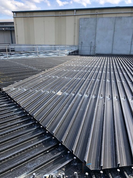 A close up of a metal roof with a large nail on building in the background