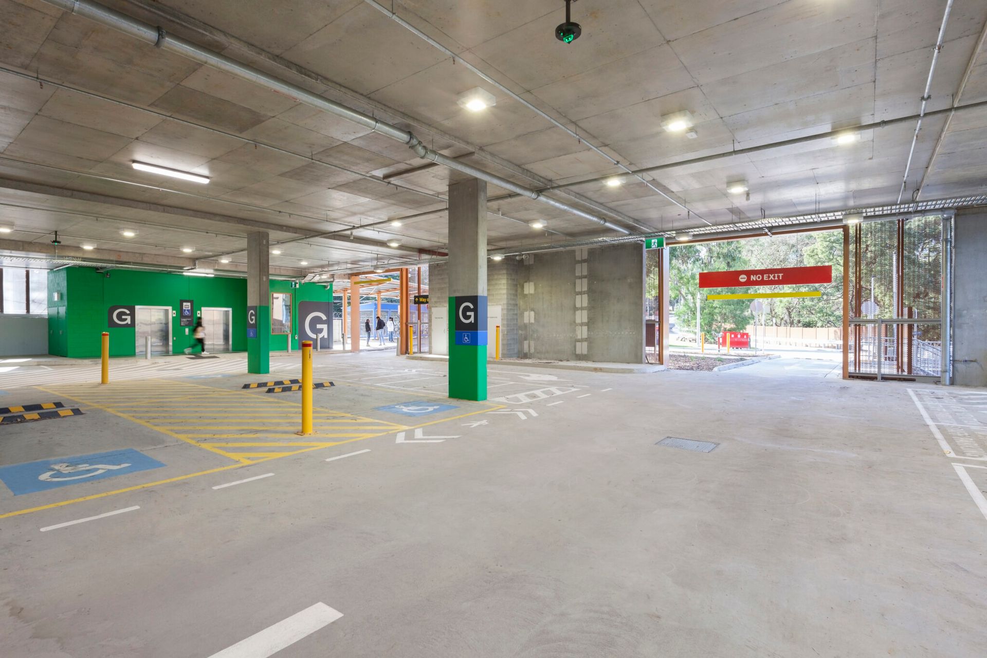 A large empty parking garage with a green sign that says g on it.