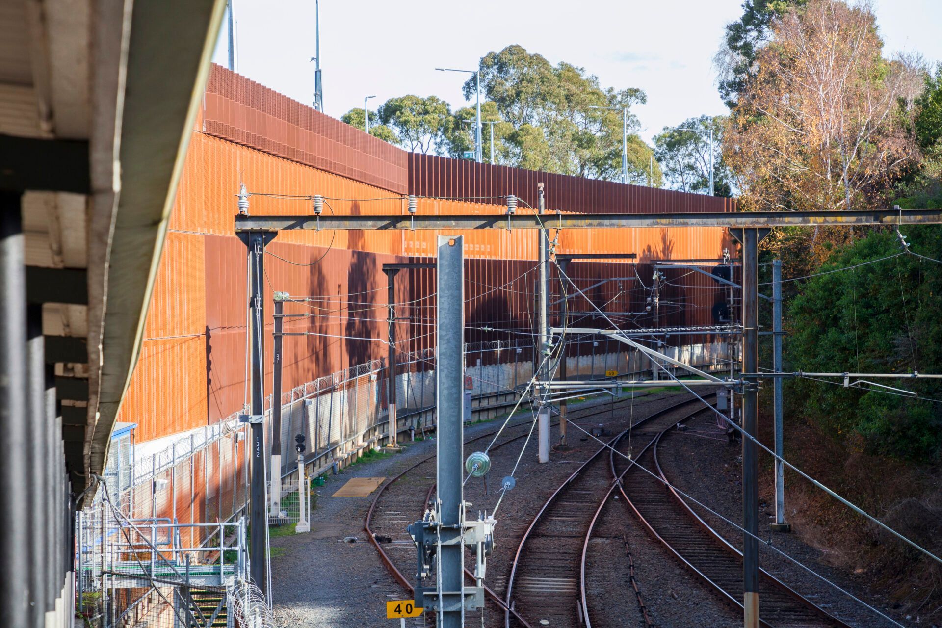 A train track with a fence and trees in the background.