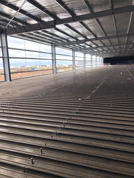 The metal decks inside of a large building with a lot of windows and stairs.
