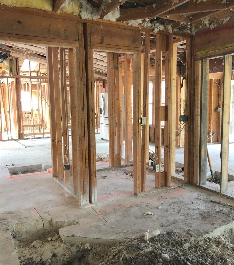 Interior framing of a room in demolition, showing exposed studs and doorways.
