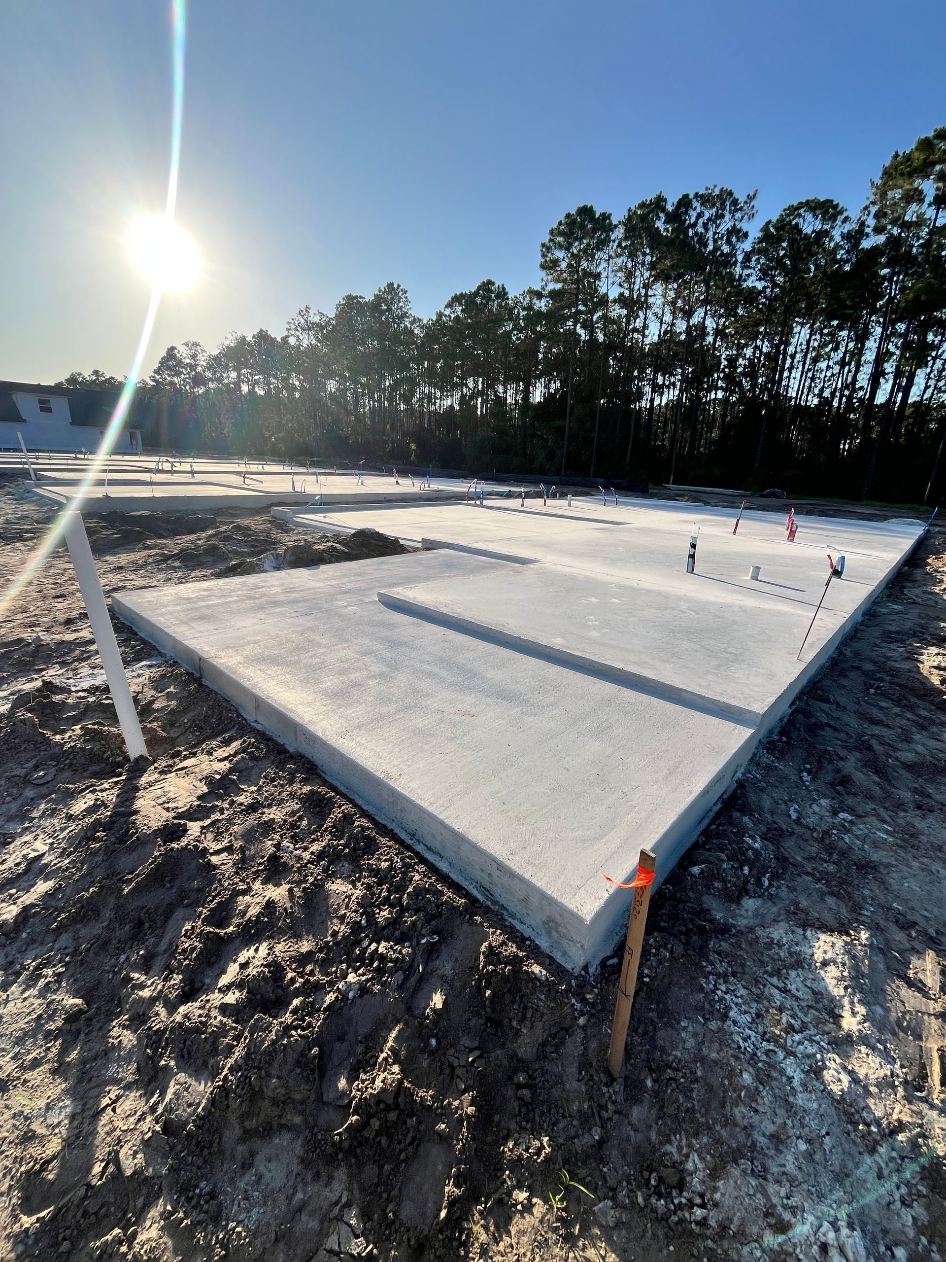 Concrete foundation for a building under construction, set outdoors on a sunny day.