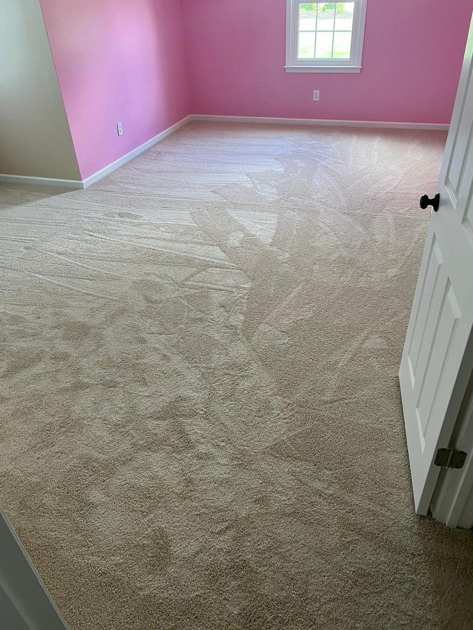 A bedroom with pink walls and a carpeted floor.