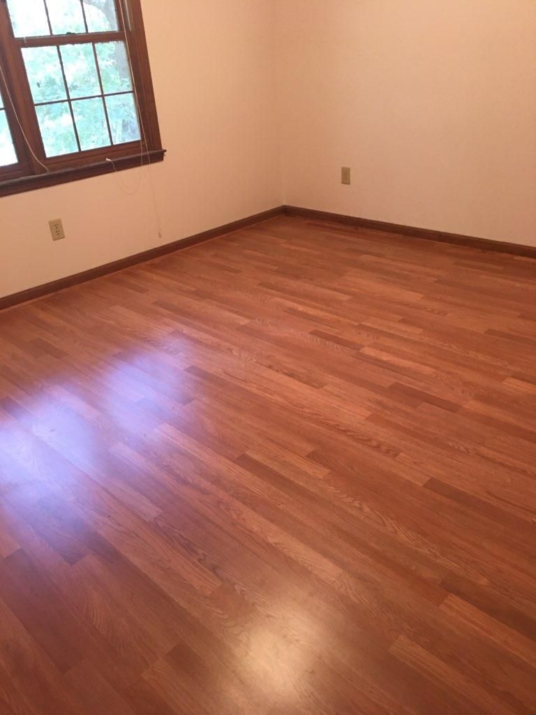 An empty room with hardwood floors and two windows.