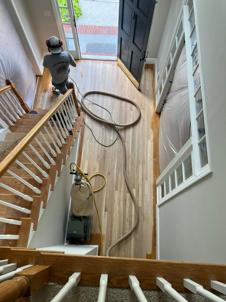 A man is working on a wooden floor in a house.