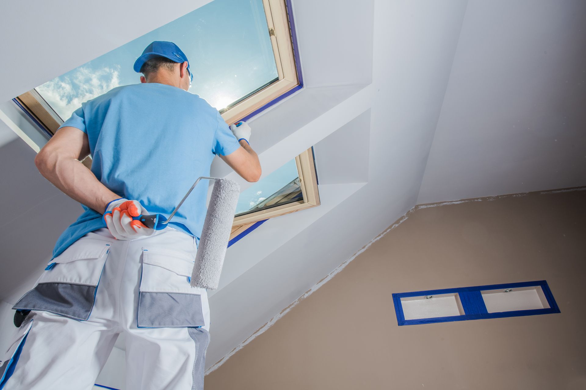 A man is standing on a ladder painting a window.