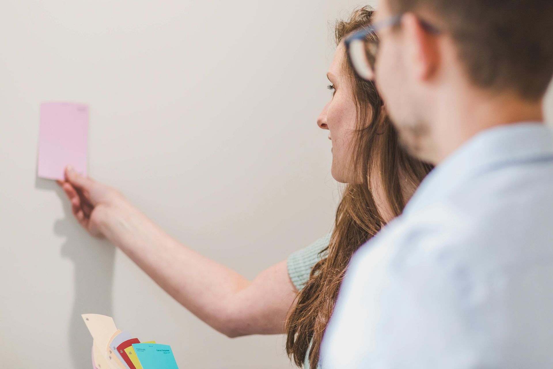 A man and a woman are looking at sticky notes on a wall.