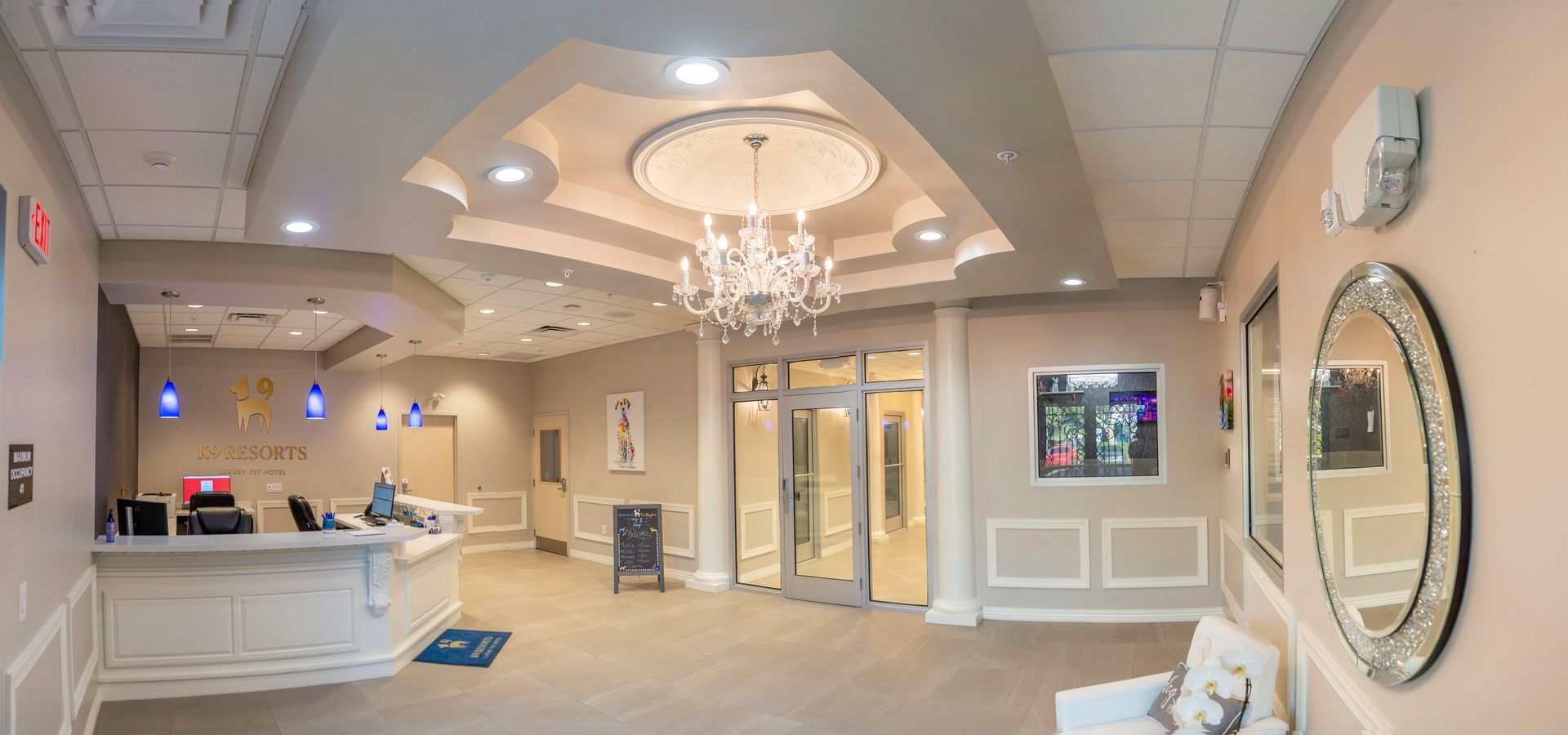 A panoramic view of a dental office with a reception desk , chairs , mirrors and a chandelier.