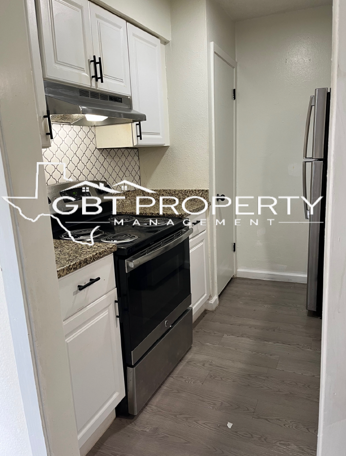 A kitchen with stainless steel appliances and white cabinets.