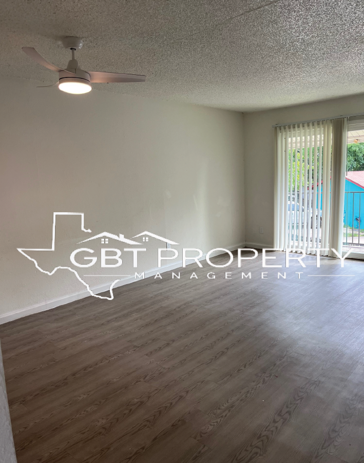 A living room with a ceiling fan and sliding glass doors.
