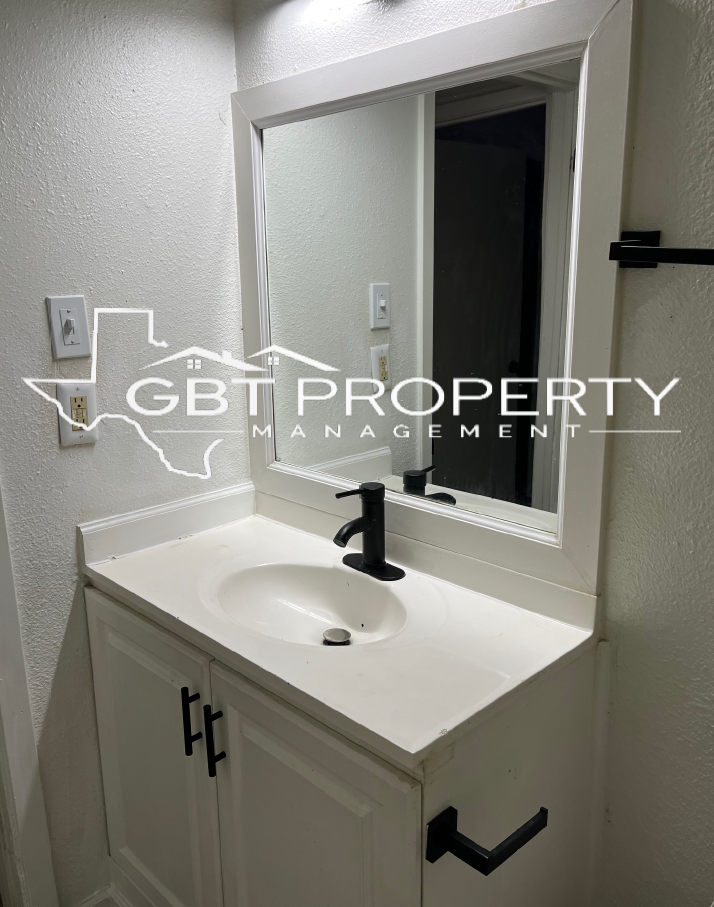 A bathroom with a sink , mirror and gbt property management logo