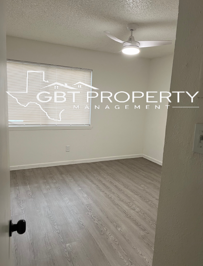An empty bedroom with a ceiling fan and a window.
