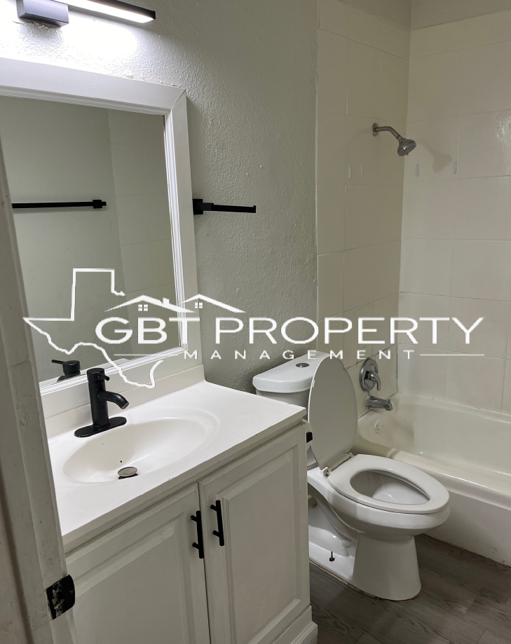 A bathroom with a toilet , sink , mirror and bathtub.