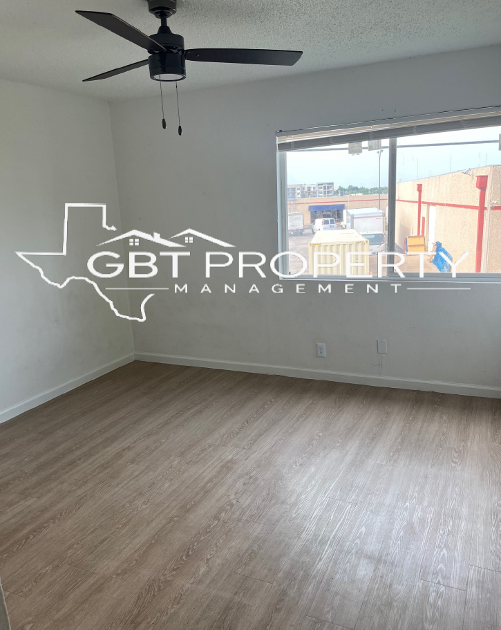 An empty room with a ceiling fan and a gbt property management logo
