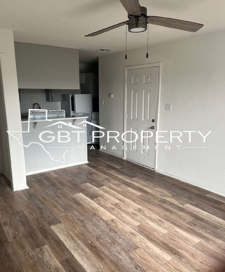 A living room with hardwood floors and a ceiling fan.