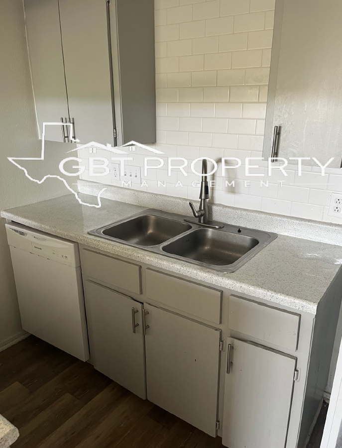 A kitchen with white cabinets , a sink , and a dishwasher.