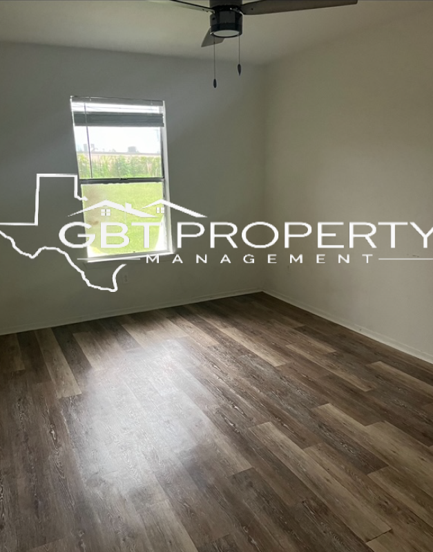 A bedroom with hardwood floors and a ceiling fan.