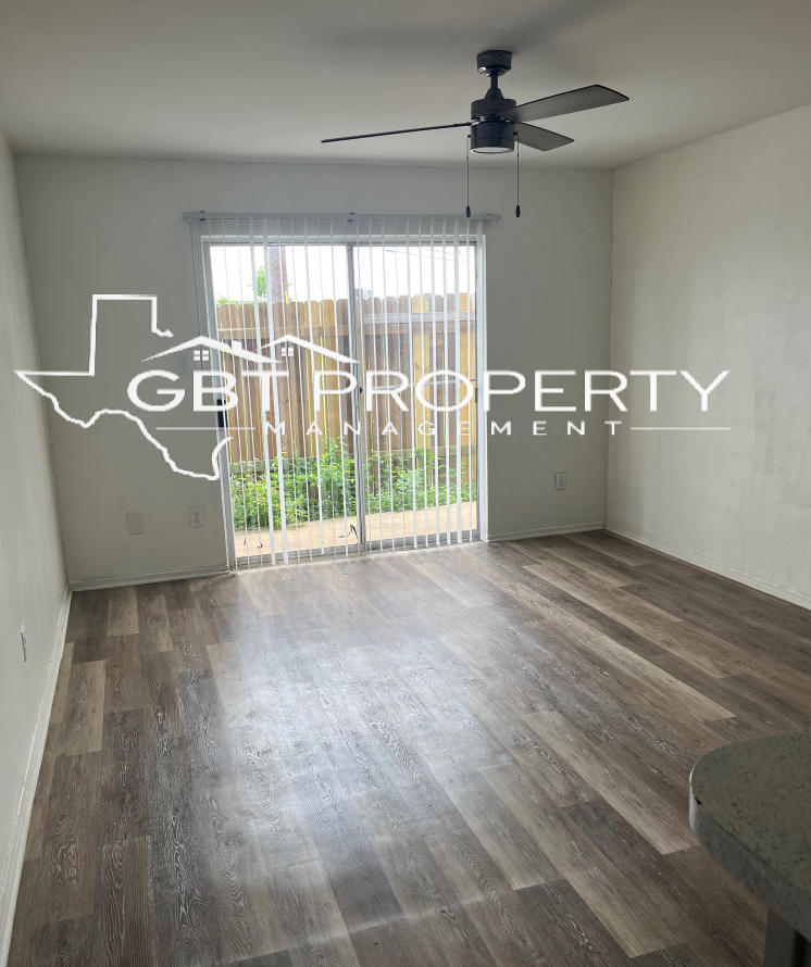 A living room with a ceiling fan and a sliding glass door.