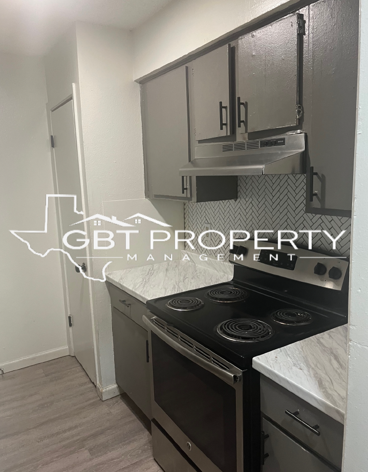 A kitchen with stainless steel appliances and gray cabinets.