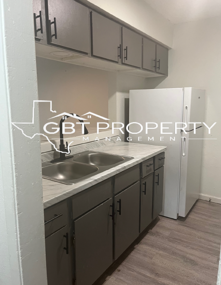 A kitchen with gray cabinets and a white refrigerator