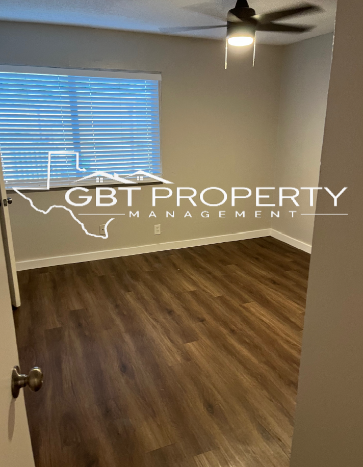 An empty bedroom with a ceiling fan and a window.