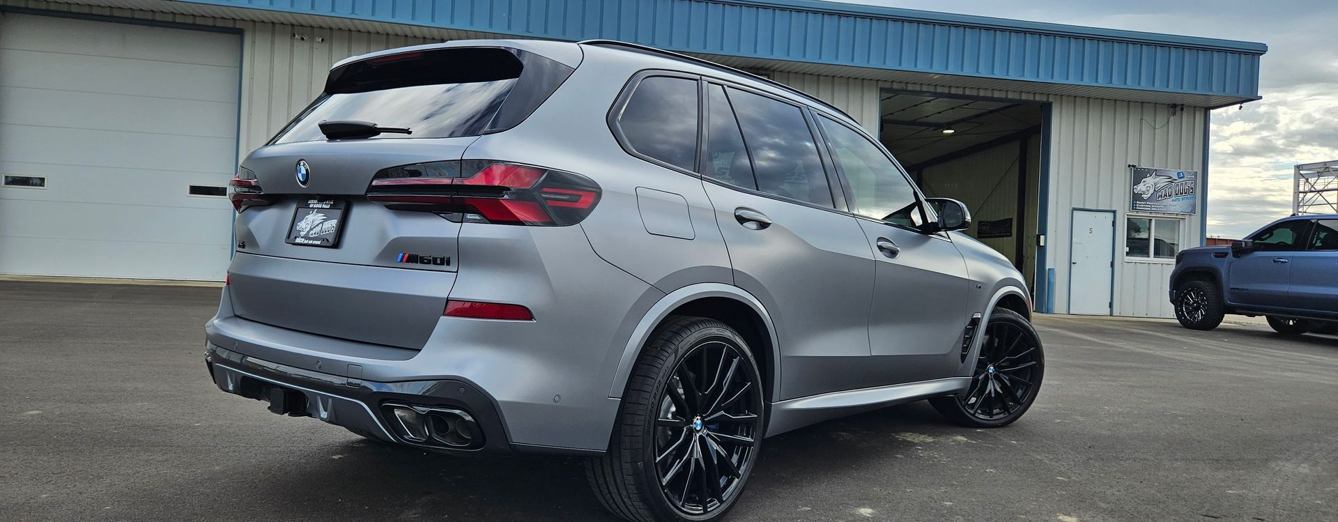 Gray BMW SUV with black wheels parked outside a building.