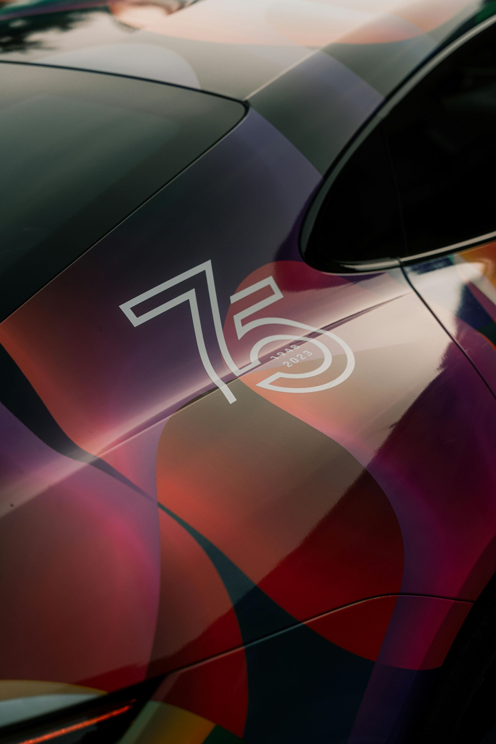 A car with a colorful wrap, the number 75 in white on the side.