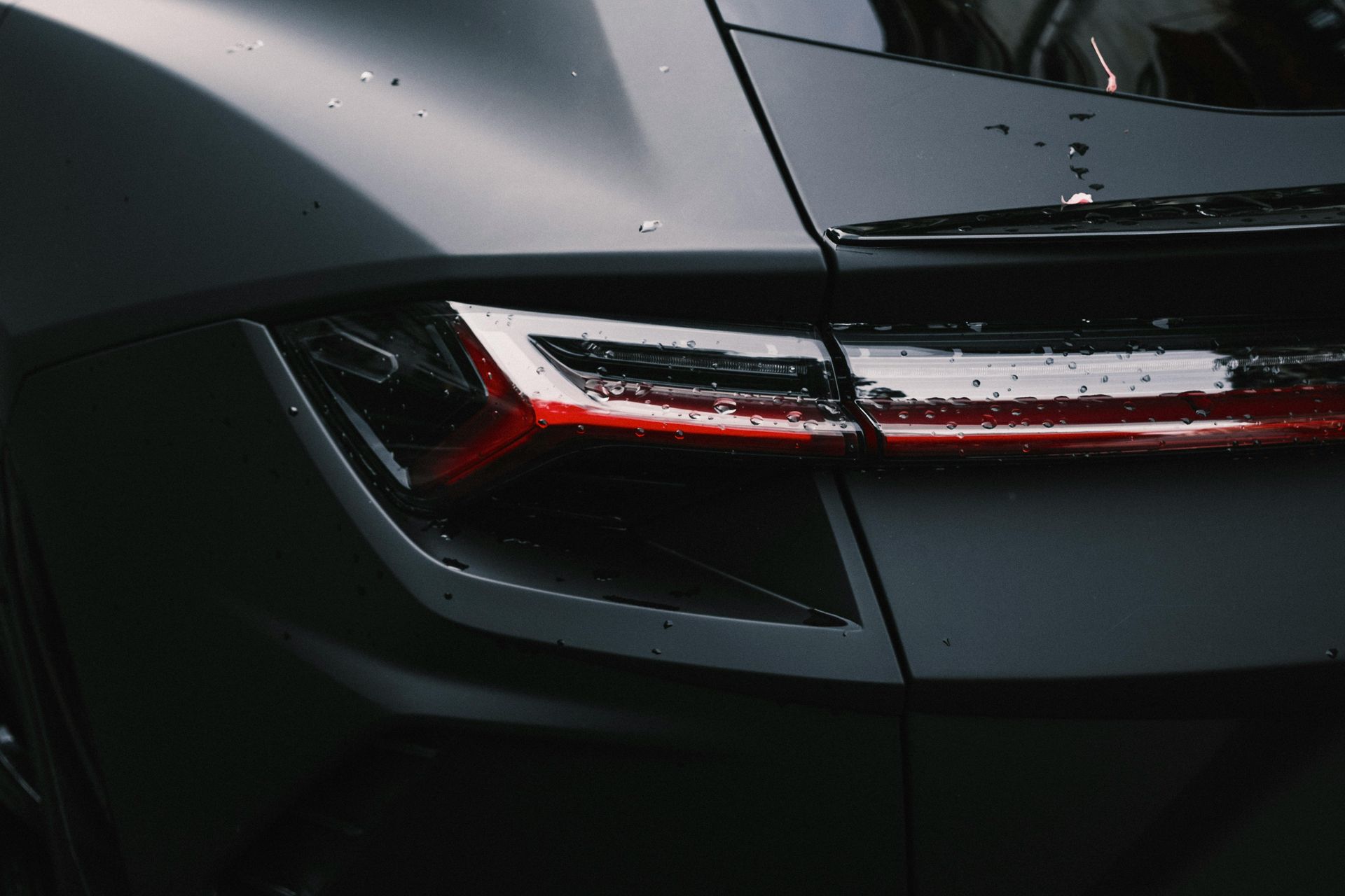 Person in black gloves applying liquid product to a blue sponge, yellow car in the background.