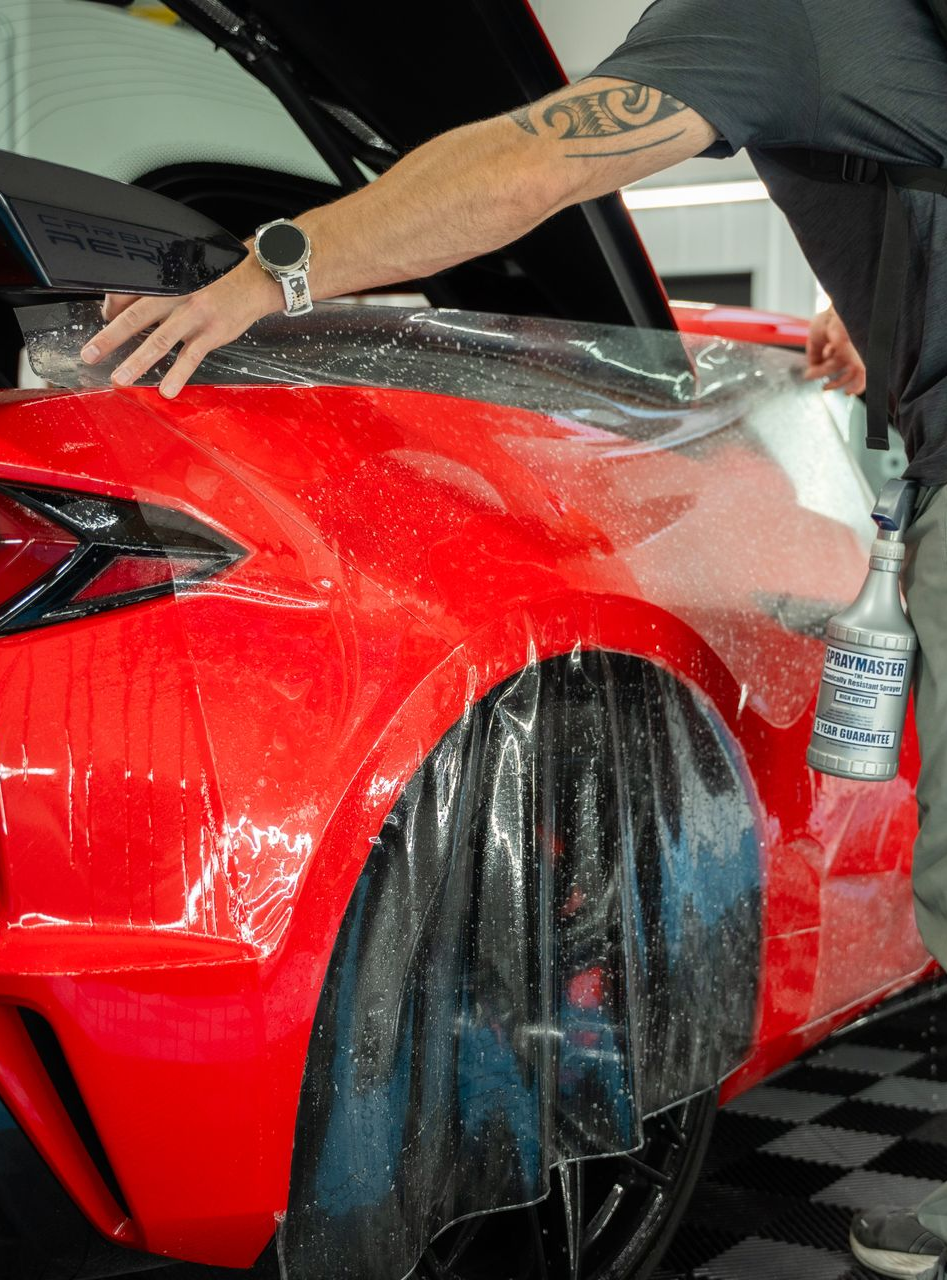 Blue car in a field with mountains and sunset.