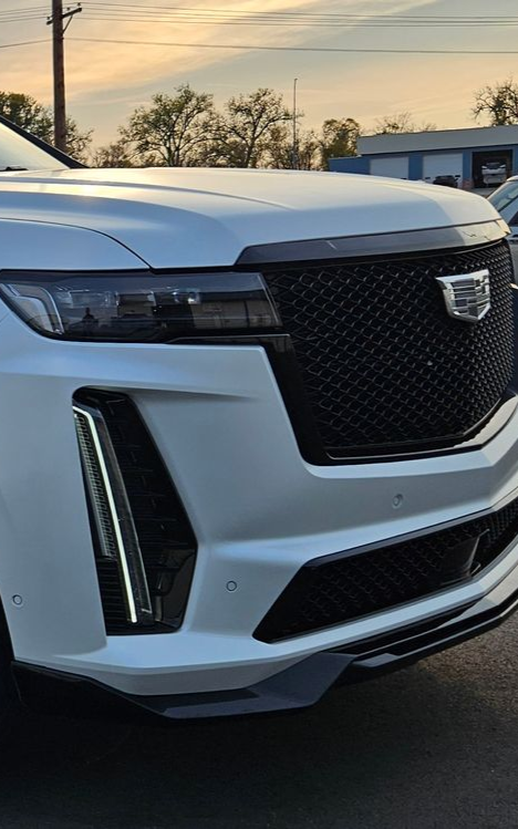 White Cadillac Escalade SUV, black grille, daytime.