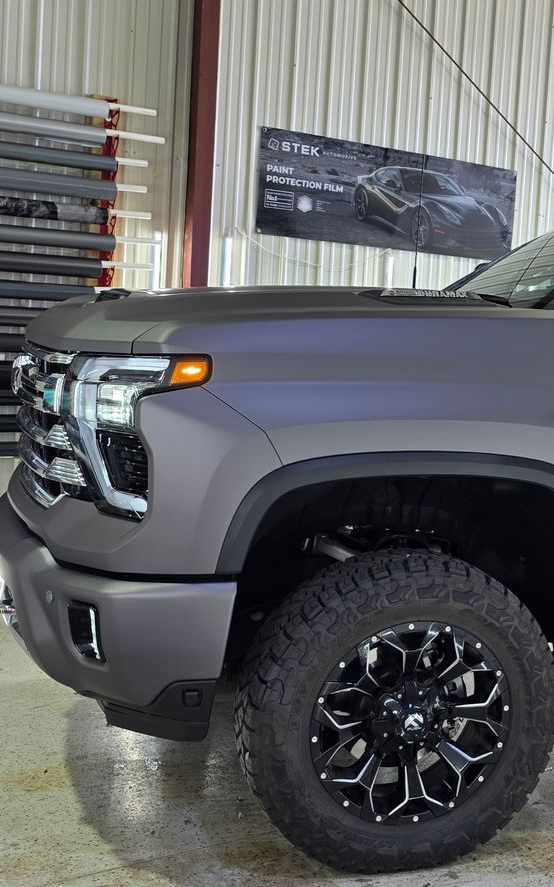 Gray pickup truck with black and silver wheels inside a garage.