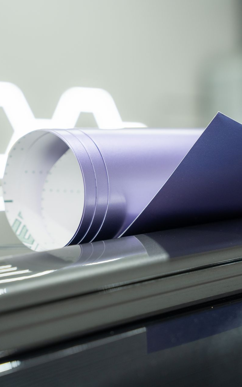 Rolled blue vinyl sheet resting on a stack of gray objects.