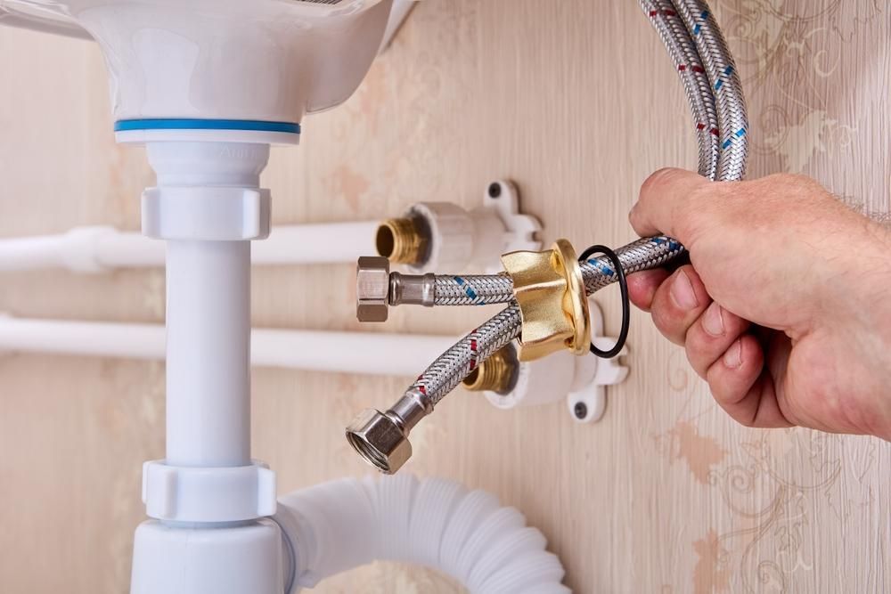 A Person Is Fixing a Sink with A Hose — Delaney Plumbing Services In Taree, NSW