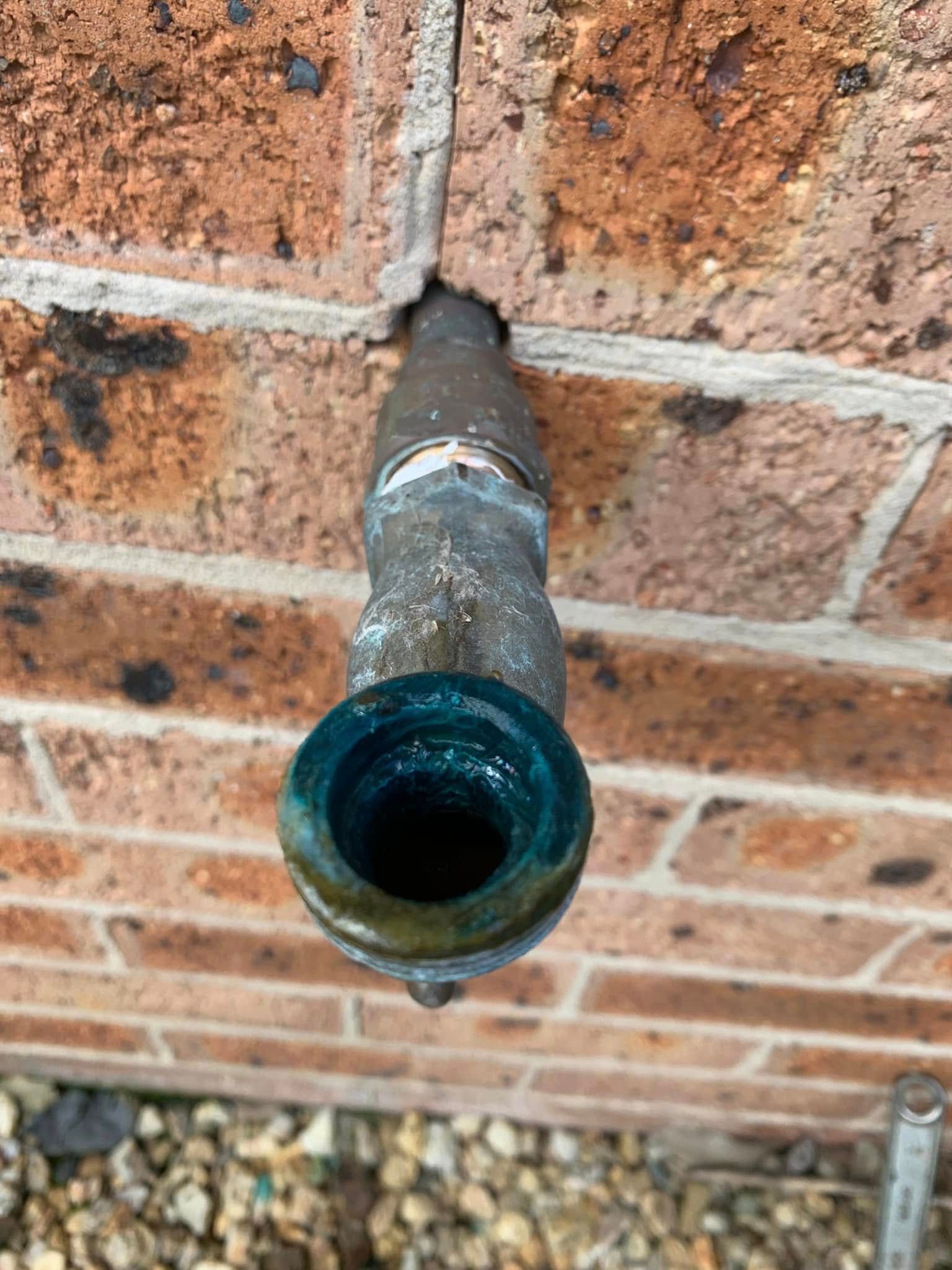 A Plumber Is Fixing a Pipe with A Wrench — Delaney Plumbing Services In Wingham, NSW