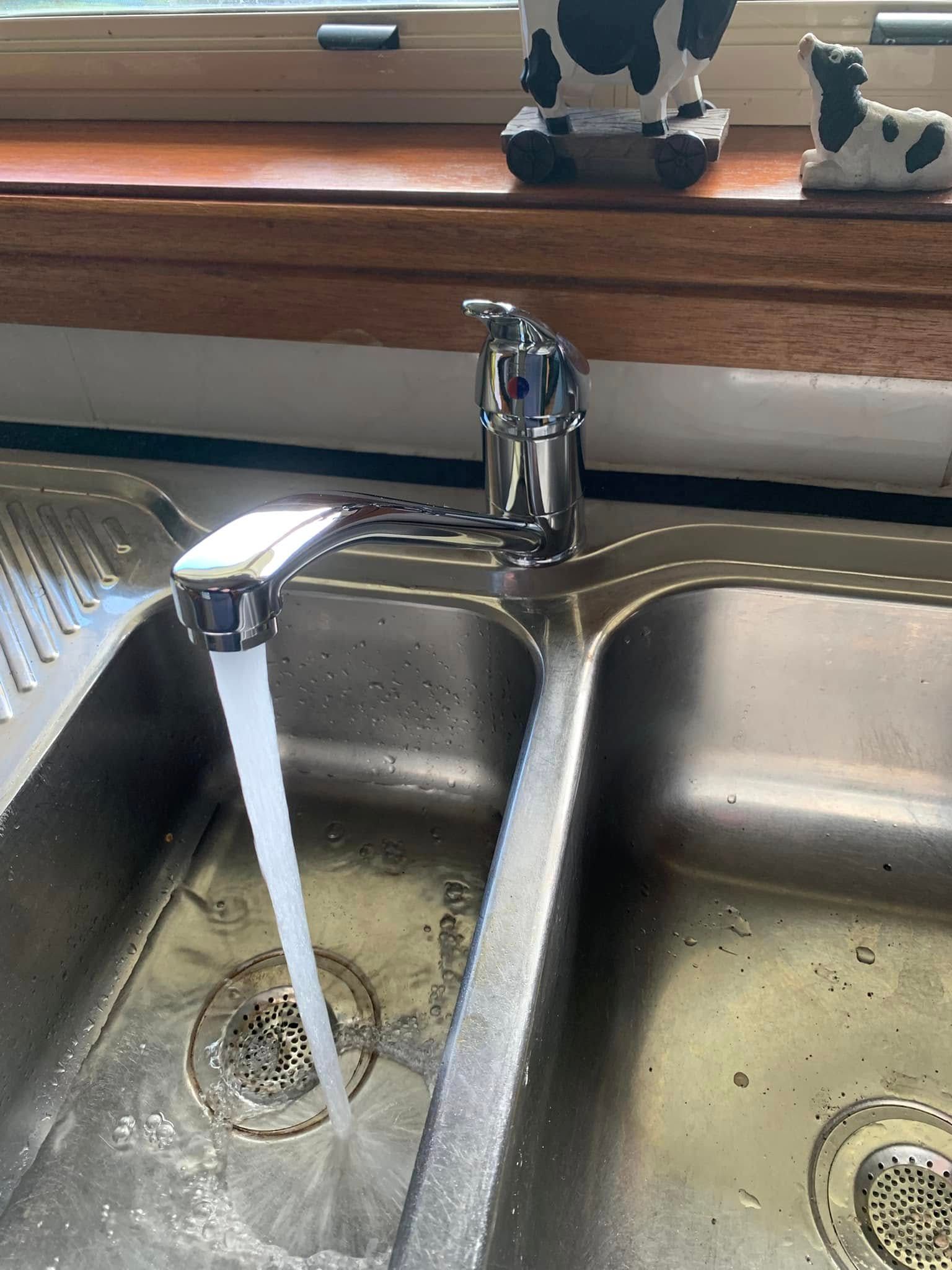 A Stainless Steel Kitchen Sink With Water Running From the Faucet — Delaney Plumbing Services In Taree, NSW