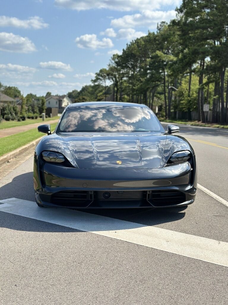 A black porsche taycan is parked on the side of the road.